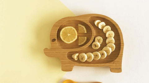 Picture of bamboo elephant plate with banana in it on a yellow background
