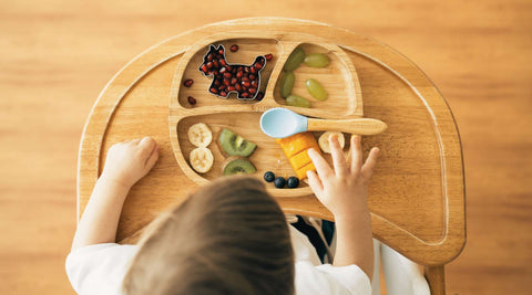 Child using eco rascals suction plate on a highchair