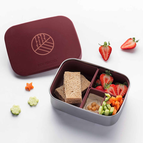 Image shows the Classic Burgundy Lunchbox by eco rascals with removable dividers and a stainless steel base with a sandwich, strawberries, humus and crudités inside. 