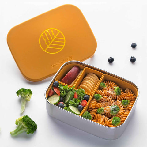 Image shows the classic Mustard eco rascals lunch box bento style with removable dividers with food inside. Pasta, salad, crackers and apple.